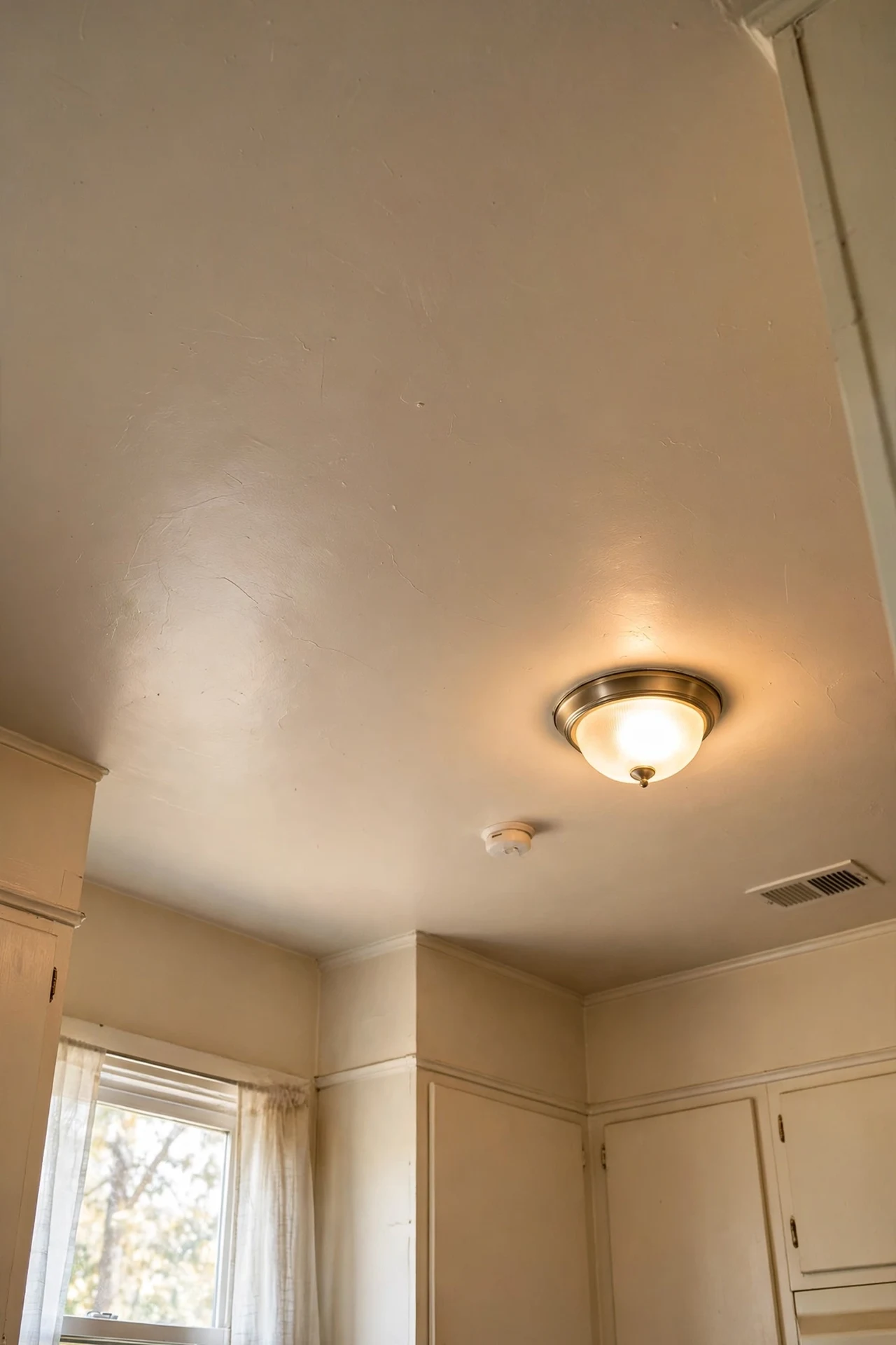 Pale beige painted kitchen ceiling softening light