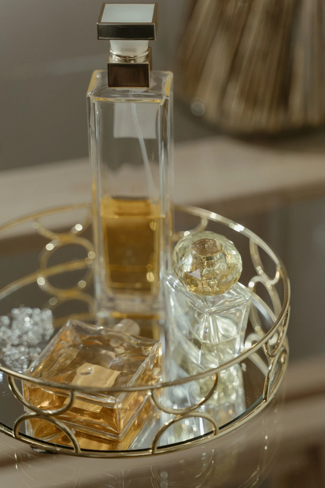 Perfume bottles arranged on a small gold mirrored tray on a bathroom vanity
