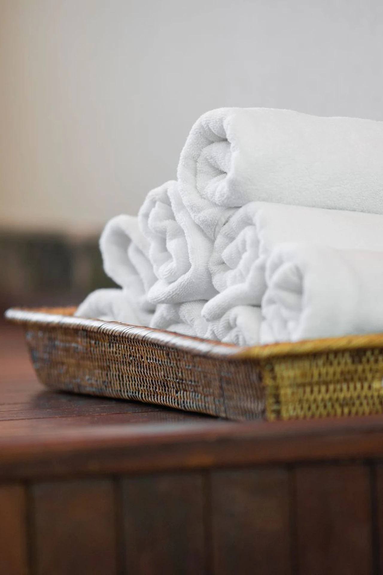 Neatly rolled white towels stacked in a basket in a spa style bathroom