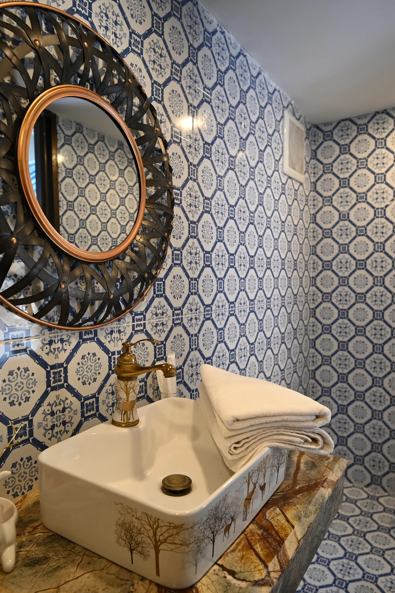 Glass soap dispenser with gold pump beside a bathroom sink