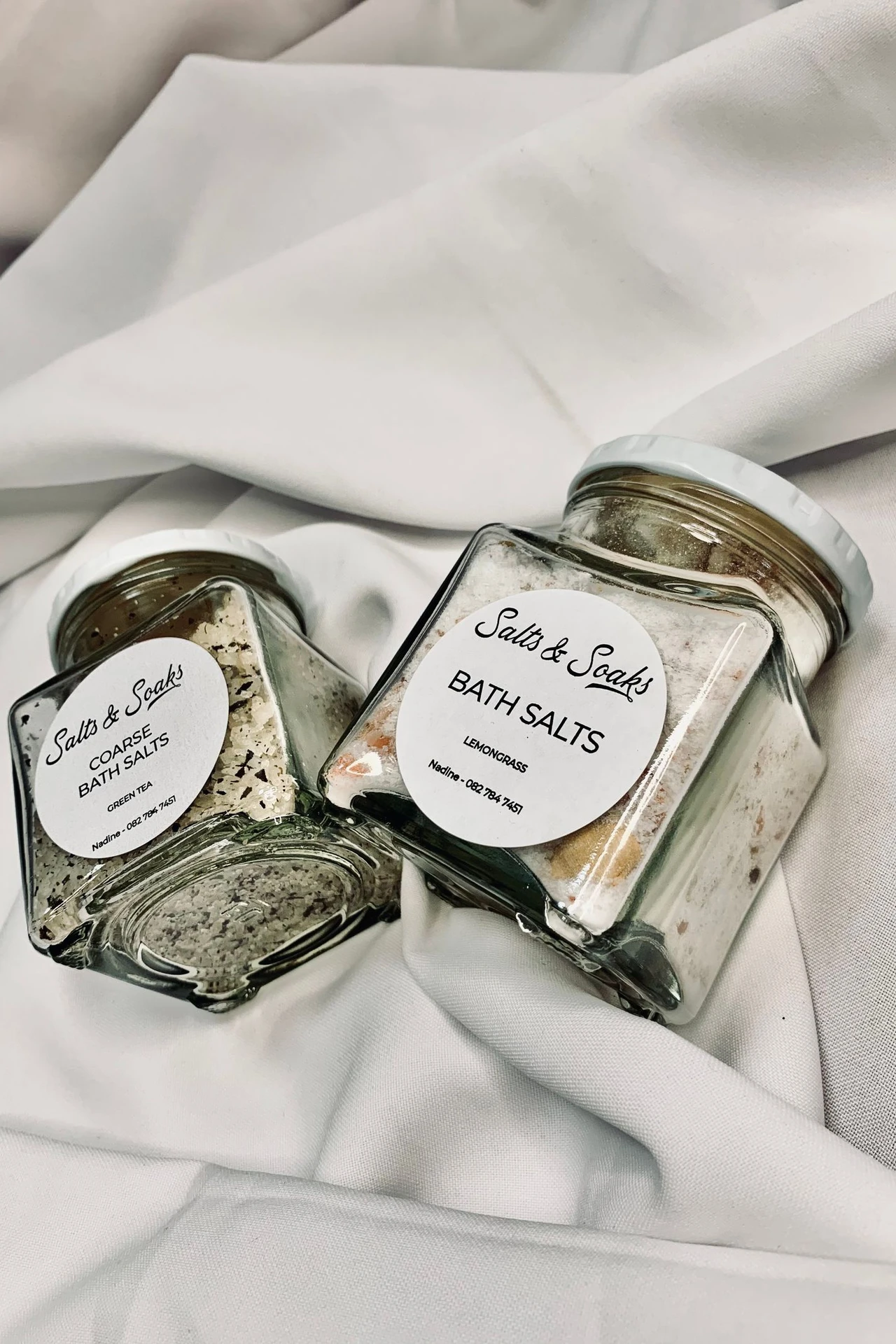 Matching glass canisters with wooden lids holding bath salts and cotton pads