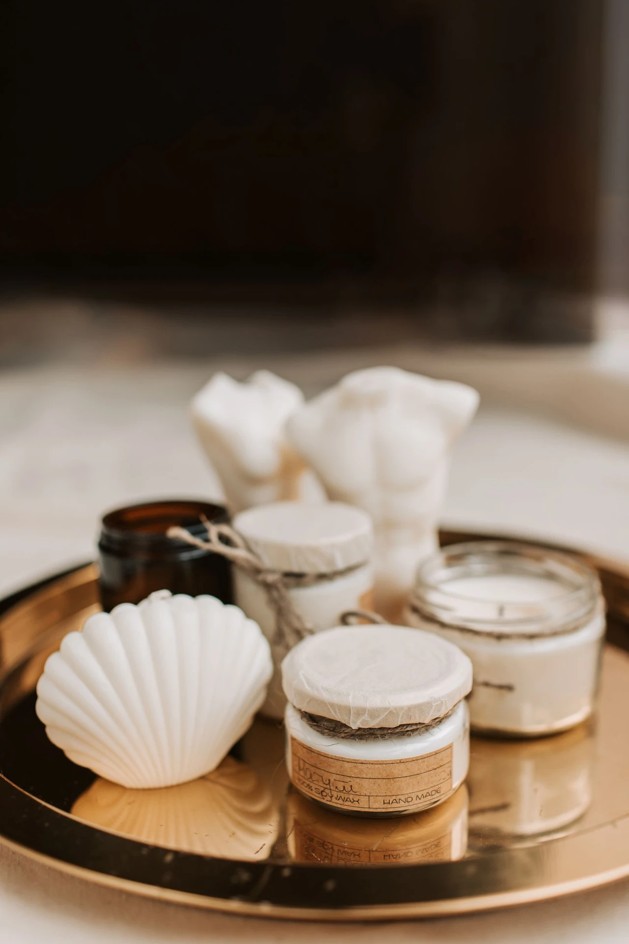 Scented candle and small plant on a gold tray on a bathroom shelf
