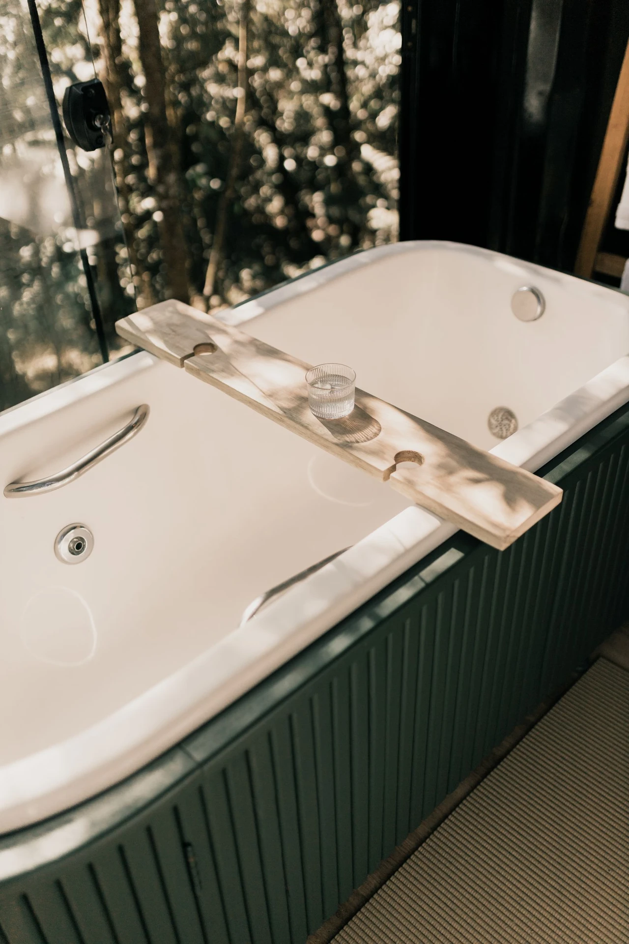 Teak bath mat beside a shower in a spa-like modern bathroom