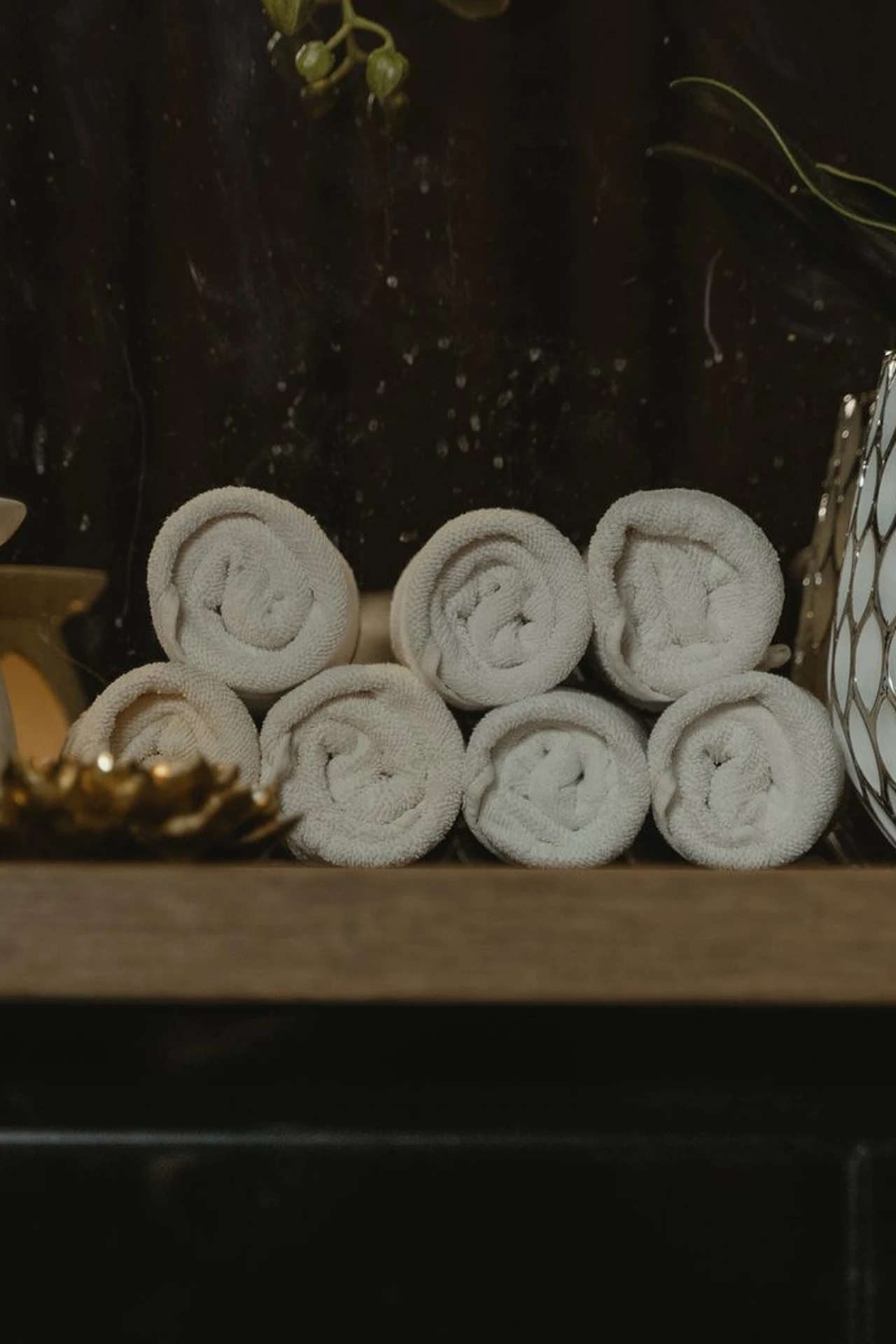 Scented candle and rolled white towels on a bathroom shelf