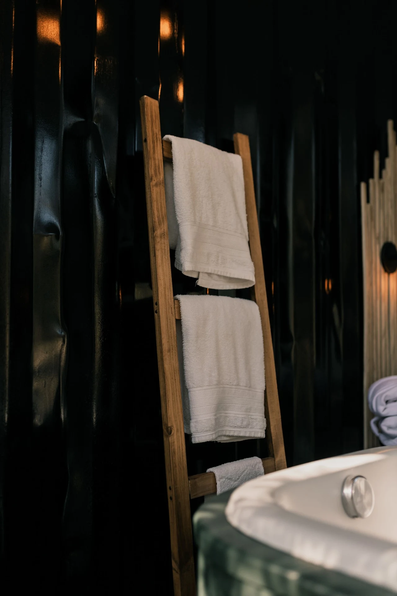 Wooden towel ladder with mustard and cream towels in a bathroom