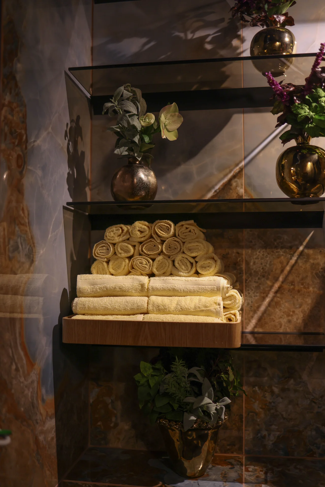 Floating wooden shelf above a toilet with a plant and rolled towel