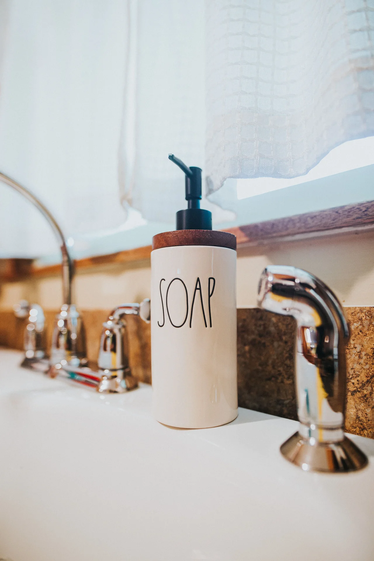 Wall-mounted soap dispenser beside a small bathroom sink