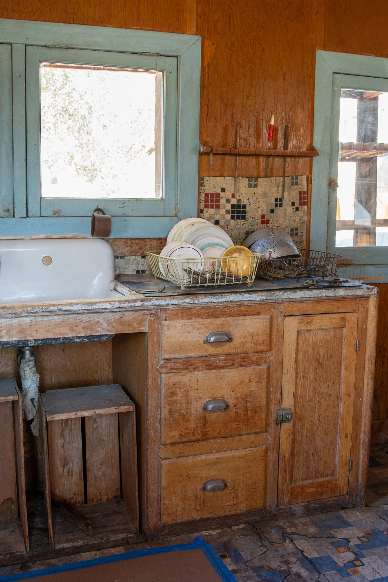 Tension rod shelf inside a deep kitchen cupboard holding cleaning supplies