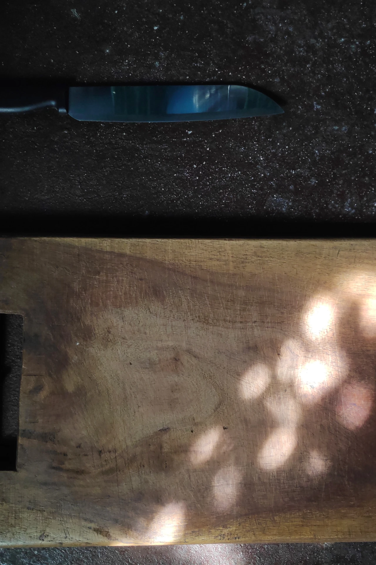 Wooden cutting board fitted over a small kitchen sink with chopped vegetables