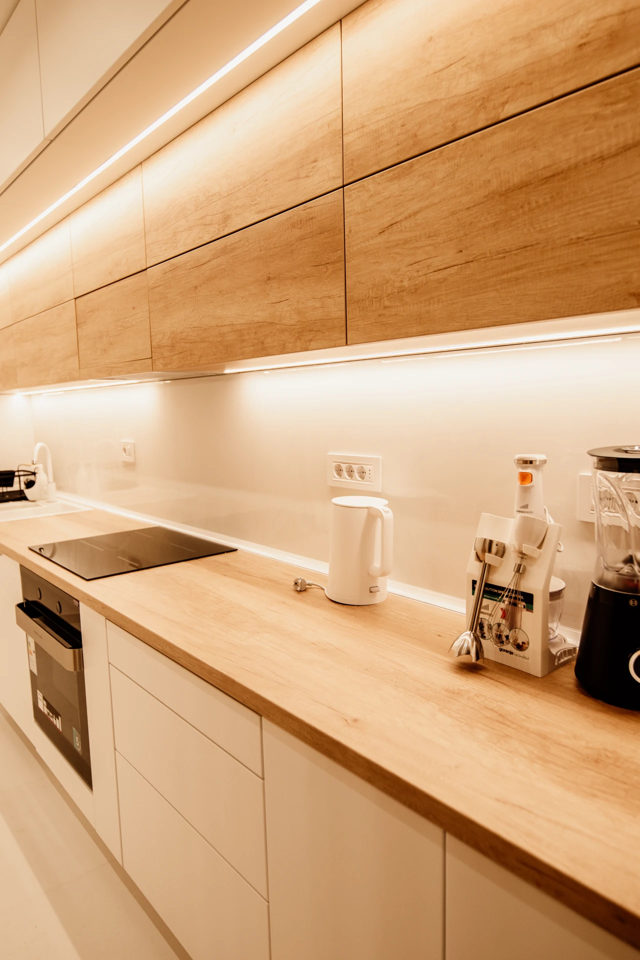 Warm under-cabinet LED lighting glowing over a small apartment kitchen counter