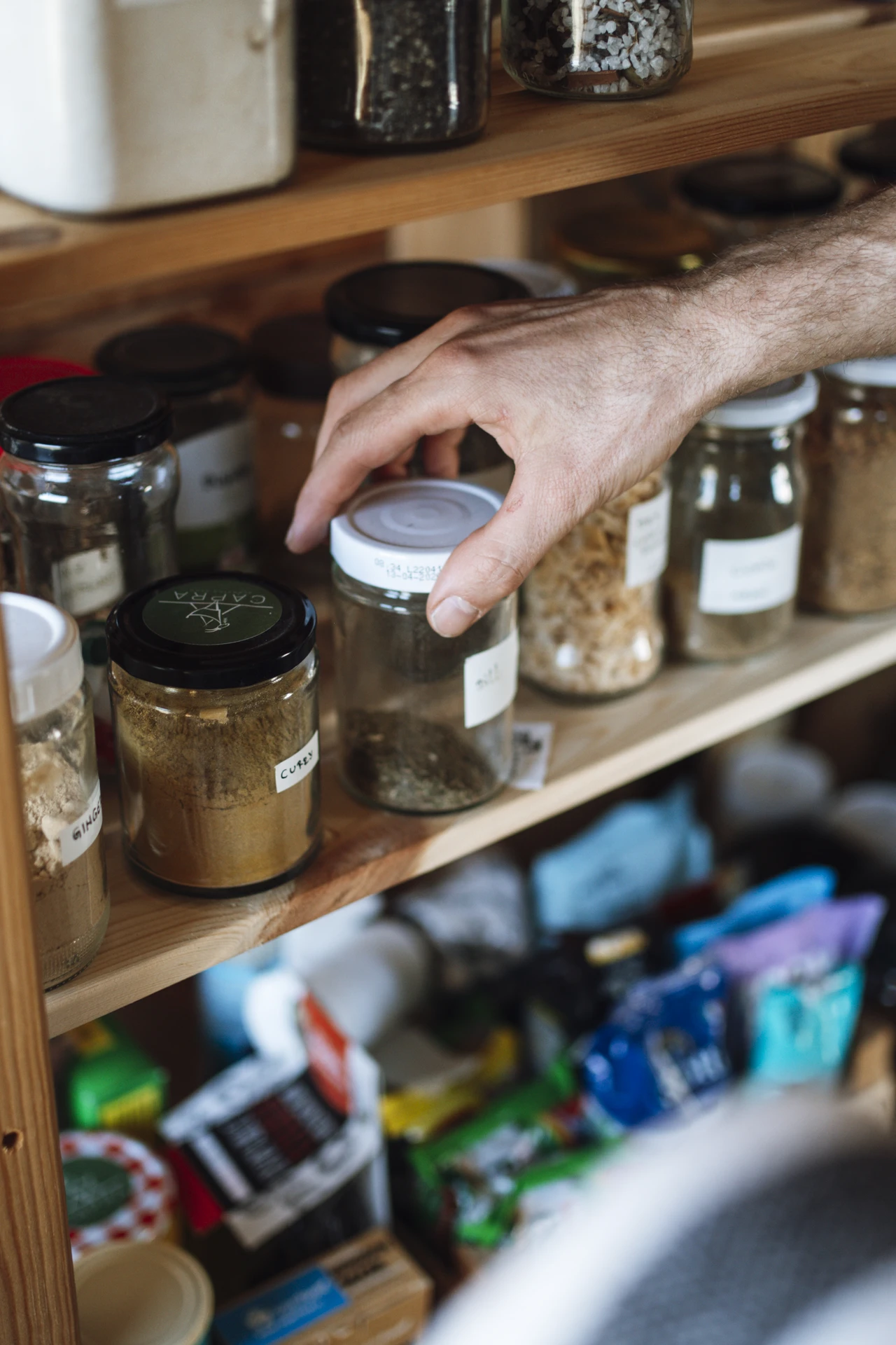 Matching labelled glass jars of flour rice and pasta on a small kitchen shelf