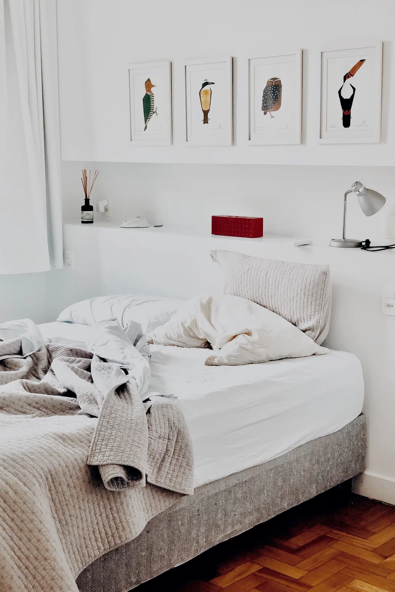 Tiny bedroom painted warm white with sunlight and a low bed