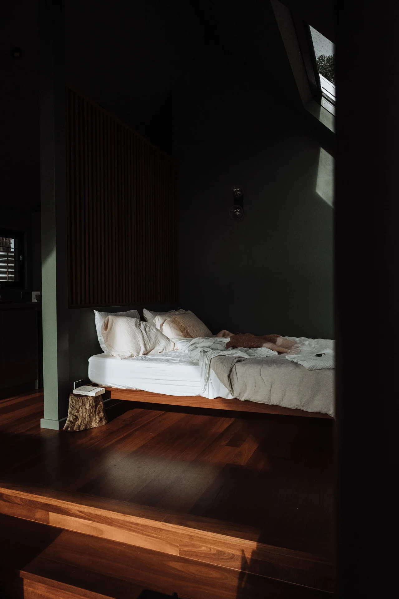 Small bedroom with a low wooden platform bed and minimal furniture