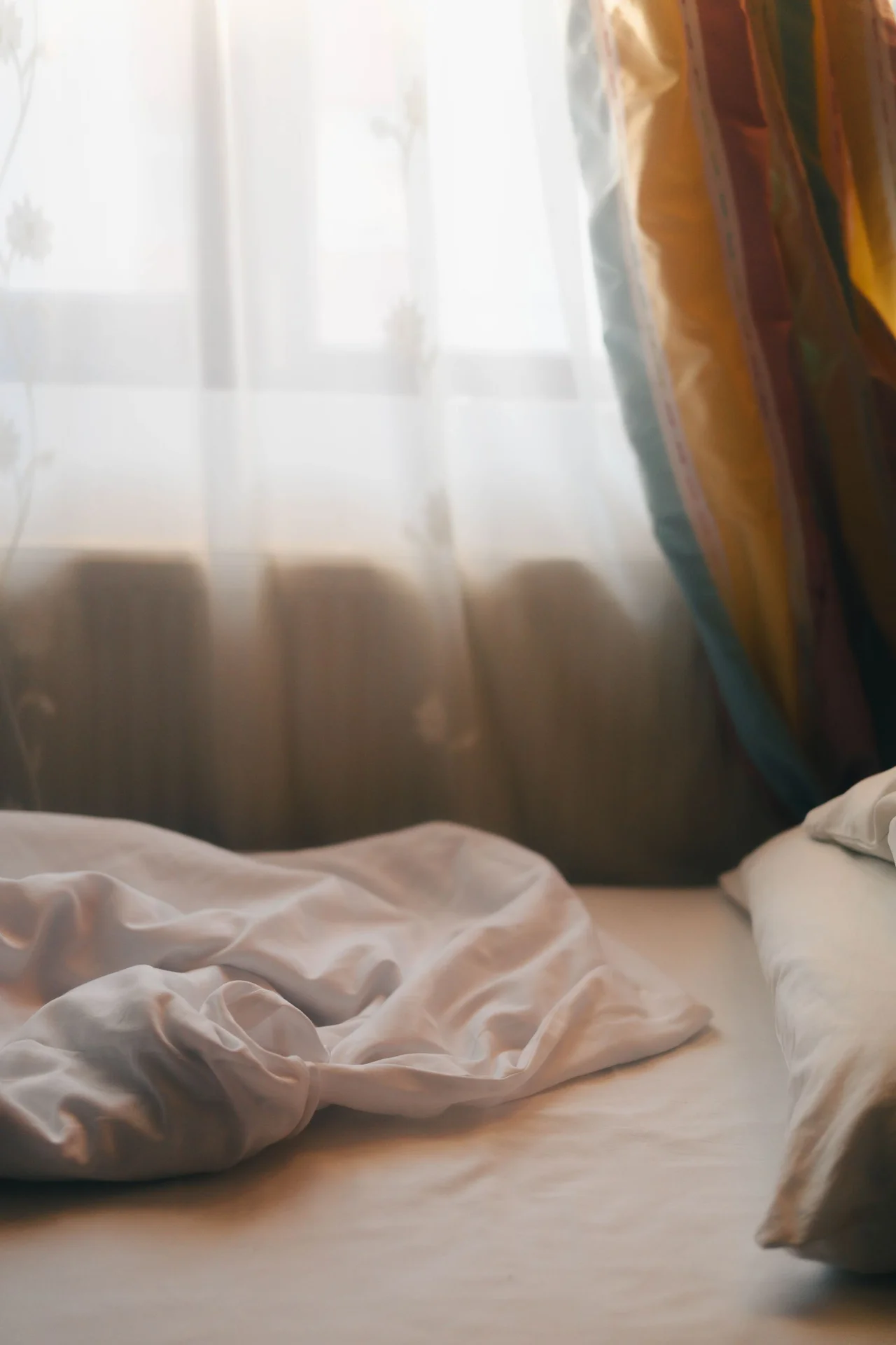 Sheer white curtains glowing in morning light in a small bedroom