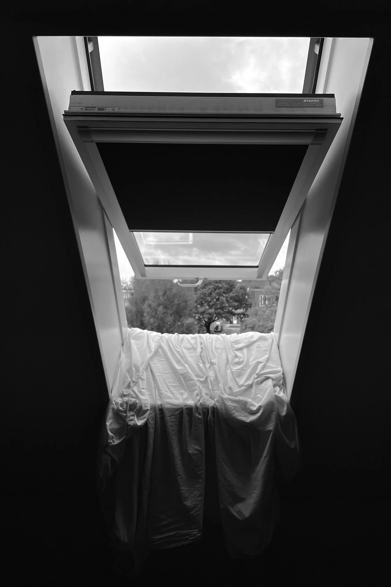 Curtains hung high near the ceiling over a small bedroom window