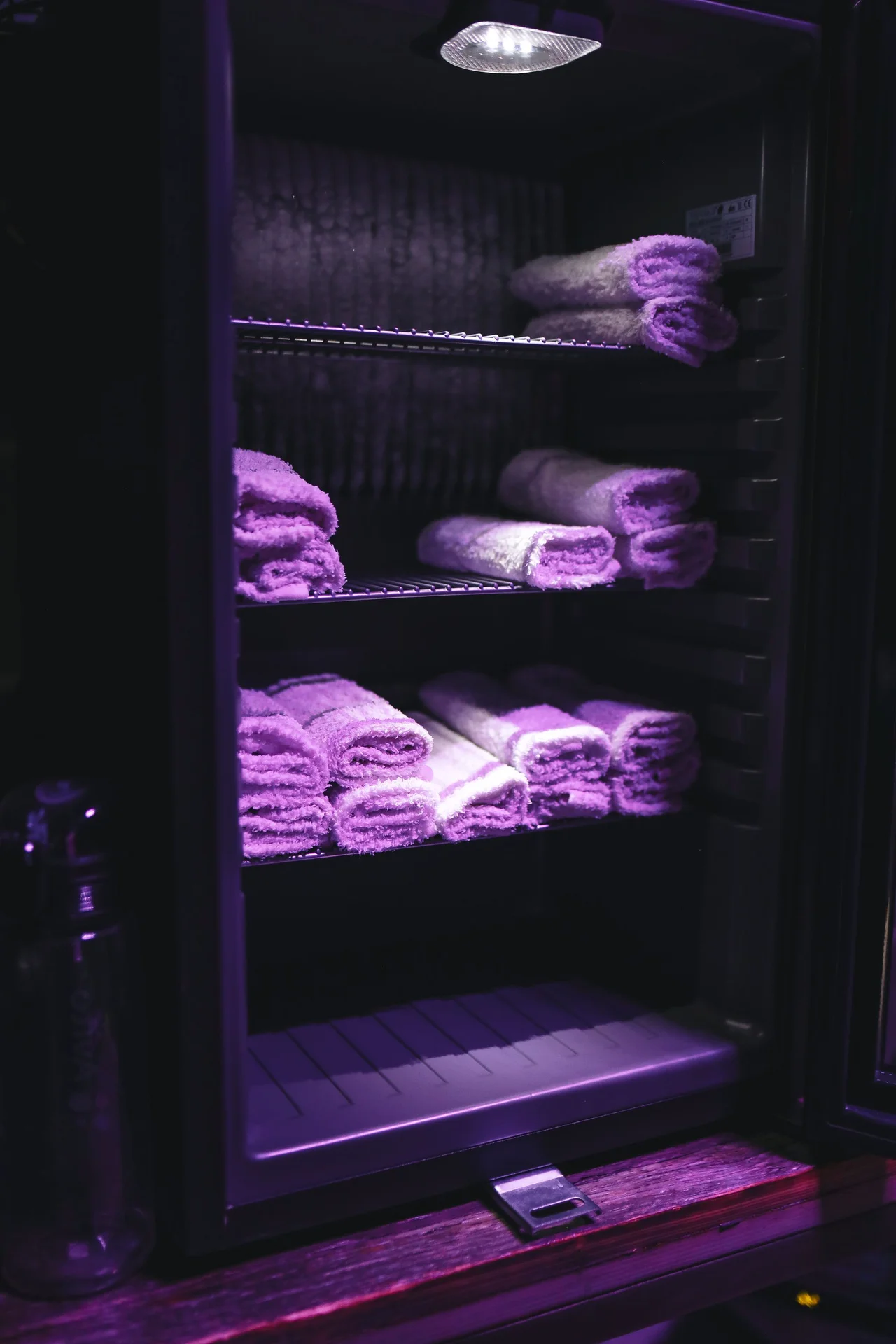 Rolled white towels displayed on a shelf in a small bathroom