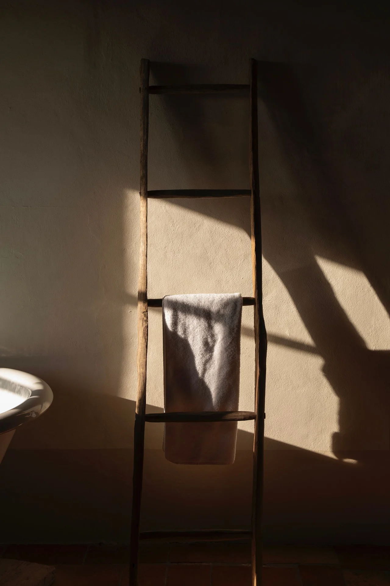 Wooden towel ladder leaning against a small bathroom wall